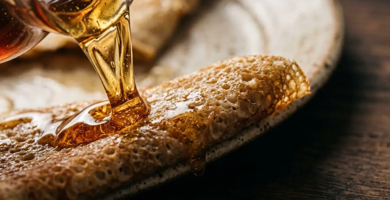 Gros plan sur du sirop d'érable coulant sur une crêpe traditionnelle québécoise