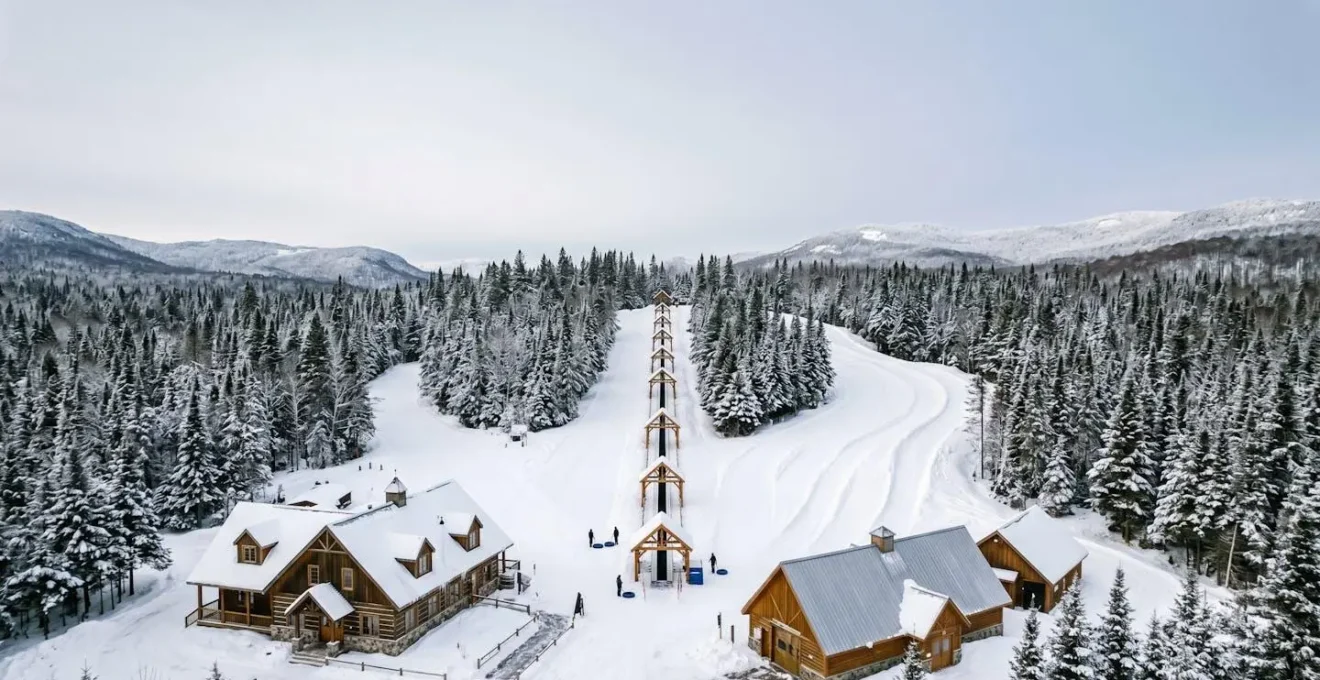Vue large et minimaliste d'un centre de glissade hivernal québécois avec remontées mécaniques dans un paysage enneigé